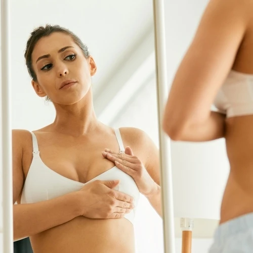 woman wearing a bra, doing a self-examination for breast cancer